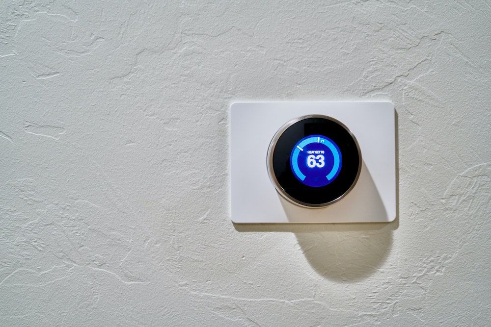 A smart thermostat on a white wall.